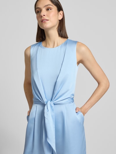 Vrouwenmodel draagt 'Jumpsuit aus Satin mit Bindegürtel' van Christian Berg Cocktail in lichtblauw satijn, licht getailleerde fit, ronde hals, satijnen riem in de taille, rechte pijpen, naadrits achter, detailopname bovenlichaam.