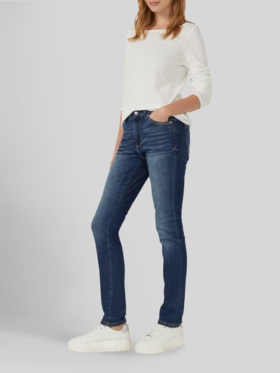 Frauenmodel trägt Slim Fit Jeans aus Baumwoll-Mix Modell 'BETSY SLIM' von s.Oliver RED LABEL in dunklem Blau mit weißem Oberteil, Ganzkörperansicht von vorne. Damen Skinny Fit Jeans von s.Oliver RED LABEL.