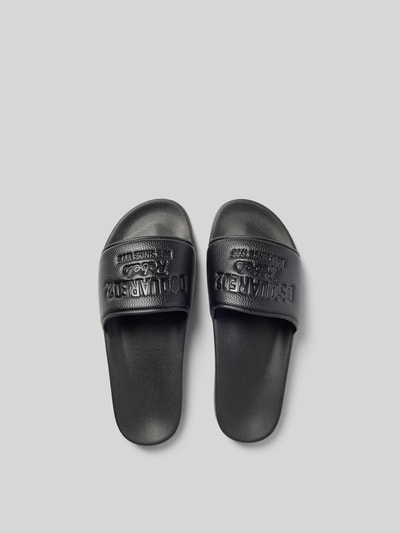 Produktfoto, schwarze Slides mit Label-Prägung von Dsquared2, abgerundete Form, offene Ferse, Strukturmuster, glatte Sohle.