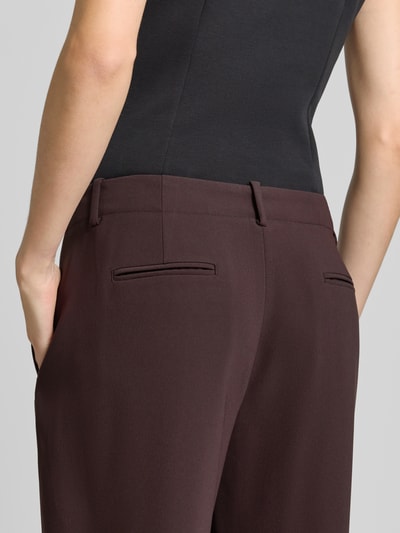 Frauenmodel trägt Relaxed Fit Stoffhose mit Kellerfalten von Armani Exchange, dunkelbraun, glatte Textur, Detailaufnahme Gesäßtaschen, Damen Stoffhose, Umgeschlagene Beinabschlüsse, Bundweite 42 cm, Innenbeinlänge 78 cm.