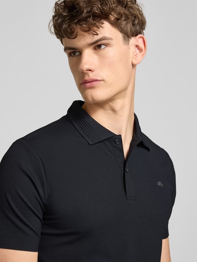 Männermodel trägt Slim Fit Poloshirt mit Logo Modell 'EDMOND' von Ellesse im schwarzen Material-Mix mit Stretch-Anteil, Nahaufnahme Oberkörper.