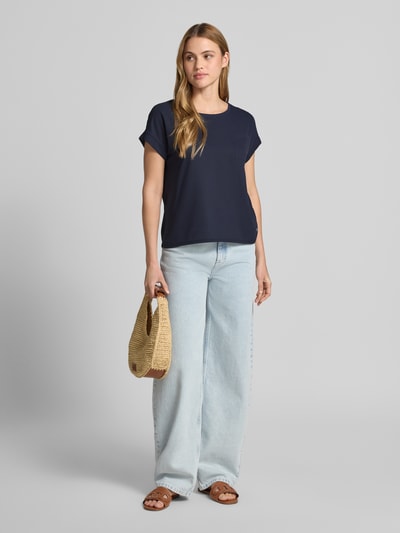 Frauenmodel trägt Blusenshirt mit verlängertem Rücken und Brusttasche von monari, Dunkelblau, Gerader-Schnitt, Rundhalsausschnitt, Ärmel mit Aufschlag, Label-Detail, Ganzkörperansicht von vorne.