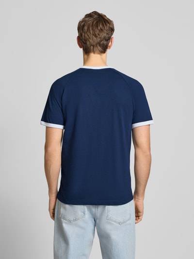 Männermodel trägt T-Shirt mit Label-Stitching von adidas Originals in Blau mit weißen gerippten Abschlüssen, Regular-Fit, Rückenlänge 73 cm, Reine Baumwolle, Ganzkörperansicht Rückansicht.