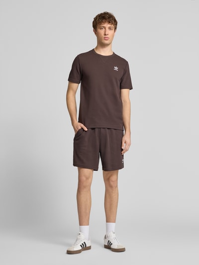 Männermodel trägt Regular Fit T-Shirt mit Baumwoll-Anteil Modell 'AUCO' von adidas Originals in Optik: Unifarben, strukturierte Piqué-Oberfläche, Label-Stitching-Applikation, Rundhals, Kurzarm, Material-Mix, Ganzkörperansicht von vorne.
