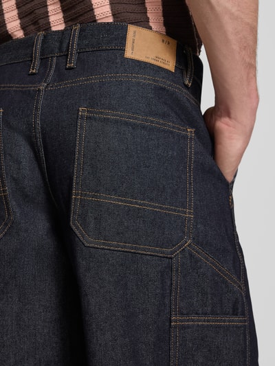 Männermodel trägt Baggy Fit Jeansshorts Modell 'ARAGON' von Redefined Rebel aus Reine Baumwolle, dunkelblau, Eingrifftaschen, Detailaufnahme. Kontext: Herren Jeansshorts, Bundweite 50 cm, Innenbeinlänge 33 cm, Größe M.