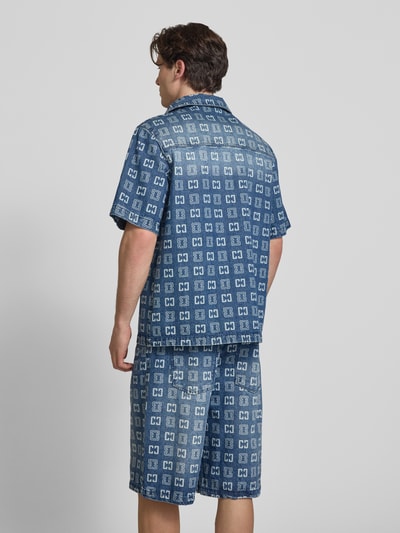 Männermodel trägt Relaxed Fit Freizeithemd in Denim-Optik mit Allover-Logo-Print von COLUCCI, blau gemustert, kurzärmelig, Ganzkörperansicht Rückansicht.