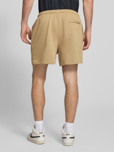Männermodel trägt Regular Fit Sweatshorts aus Baumwoll-Mix von Nike in Beige mit glatter Textur, Herren Sweatshorts, Ganzkörperansicht Rückansicht.