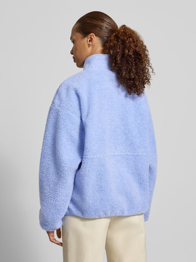 Frauenmodel trägt Regular Fit Jacke aus Teddyfell Modell 'Hoktown' von American Vintage in Hellblau, weiche Struktur, Ganzkörperansicht Rückansicht, Damen Jacke mit Stehkragen, Logo-Patch, Eingrifftaschen, Reißverschluss, Maße bei XS/S: Rückenlänge 62 cm, Schulterbreite 54 cm, Brustweite 46 cm, Ärmellänge 55 cm.