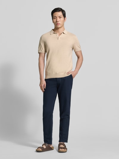 Männermodel trägt Regular Fit Poloshirt aus reiner Baumwolle Modell 'BERG' von SELECTED HOMME in Beige, unifarben, Ganzkörperansicht von vorne.