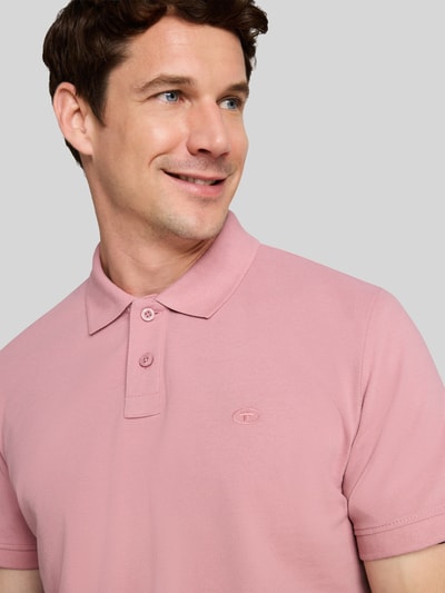 Männermodel trägt Regular Fit Poloshirt aus Baumwoll-Mix von Tom Tailor in Rosa mit glatter Struktur, Nahaufnahme Oberkörper, Herren Poloshirt von Tom Tailor.
