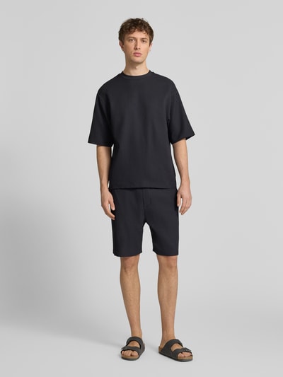 Männermodel trägt Regular-Fit T-Shirt in Plissee-Optik von REVIEW, Herren T-Shirt, Material-Mix mit Stretch-Anteil, Rundhalsausschnitt, schwarze Farbe, glatte Plissee-Textur, Rückenlänge 68 cm bei Größe M, Ganzkörperansicht von vorne.