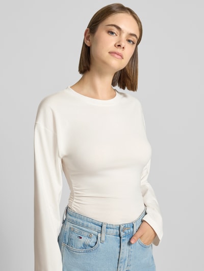 Modelka nosi bluzkę z długim rękawem z mieszanki bawełny, taliowany krój, okrągły dekolt, Longsleeve aus Baumwoll-Mix Modell 'Paloma' od JJXX, długość tyłu w rozmiarze S: 57 cm, jasny kolor, gładka tekstura, widok całej sylwetki z przodu.
