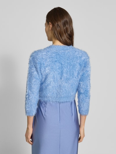 Frauenmodel trägt Bolero aus Kunstfell mit Viskose-Anteil von V.M. in hellblauem Material-Mix, 3/4-Arm, Rückenlänge 36 cm, Ganzkörperansicht Rückansicht.