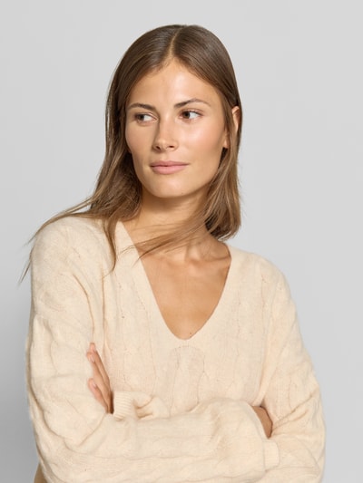 Frauenmodel trägt Relaxed Fit Pullover aus reiner Baumwolle von MYON in Beige, V-Ausschnitt, Strick-Optik, Nahaufnahme Oberkörper