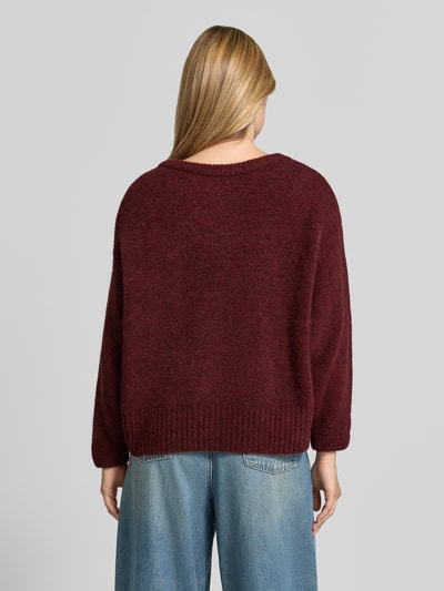 Frauenmodel trägt Oversized Pullover mit Alpaka-Anteil Modell 'East' von American Vintage, bordeaux, Strick-Optik, Ganzkörperansicht Rückansicht.