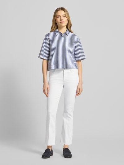 Frauenmodel trägt Bootcut Jeans mit Fransen Modell 'SHAKIRA' von Brax, weißer Baumwoll-Mix mit Stretch, verkürzte Passform, Ganzkörperansicht von vorne.