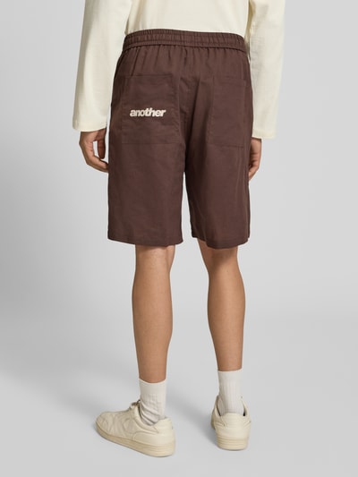 Männermodel trägt Leinenshorts mit elastischem Bund und Tunnelzug von ANOTHER COTTON LAB in Braun, Regular-Fit, Ganzkörperansicht Rückansicht. Reines Leinen, Herren Shorts, Bundweite 42 cm, Innenbeinlänge 20 cm, klare Struktur mit sichtbaren Nähten.
