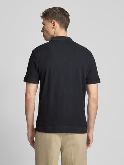 Męski model nosi Comfort Fit Poloshirt mit V-Ausschnitt von Lindbergh z bawełny, fakturowany wzór, detal z logo, długość tyłu 68 cm w rozmiarze M, widok całej sylwetki z tyłu