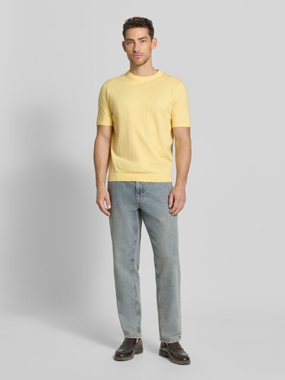 Männermodel trägt Regular Fit T-Shirt mit Leinen-Anteil in Strick-Optik von Fynch-Hatton, katoenmix, logo-stitching, gele kleur, elastische boorden, lengte achterzijde 70 cm bij maat M, volledig lichaam aan voorzijde.