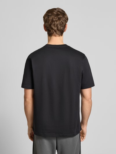 Männermodel trägt T-Shirt mit Label-Stitching von adidas Originals in Schwarz, reine Baumwolle, Regular Fit, Rückenansicht, Ganzkörperansicht Rückansicht.