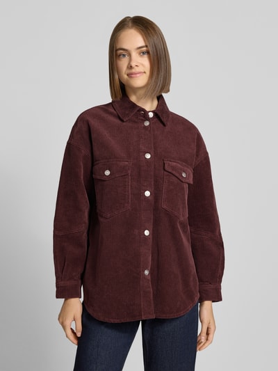Frauenmodel trägt Loose Fit Hemdjacke aus reiner Baumwolle Modell 'TIGGY' von ONLY in Bordeaux, Cord, einreihige Knopfleiste, Ganzkörperansicht von vorne.