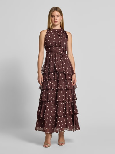 Frauenmodel trägt Abendkleid mit Rüschenbesatz Modell 'Marli' von Neo Noir in Braun mit weißen Punkten, taillierte Passform, Ganzkörperansicht von vorne.