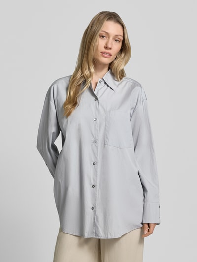 Frauenmodel trägt Oversized Hemdbluse aus reiner Baumwolle von Marc O'Polo, unifarben, Knopfleiste, Kentkragen, Ganzkörperansicht von vorne.