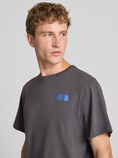 Männermodel trägt Relaxed Fit T-Shirt mit Logo-Print von The North Face aus reiner Baumwolle in Dunkelgrau mit Rundhalsausschnitt, Nahaufnahme Oberkörper.