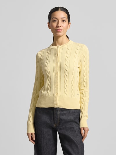 Vrouwenmodel draagt 'Strickjacke mit Zopfmuster und Rundhalsausschnitt' van JAKE*S STUDIO WOMAN van puur katoen, slim fit, kabelpatroon, ronde hals, knoopsluiting, ruglengte maat S 52 cm, mouwlengte maat S 67 cm, lichte kleur, gebreide textuur, rechte vormen, voorkant geheel zichtbaar. Ganzkörperansicht von vorne.