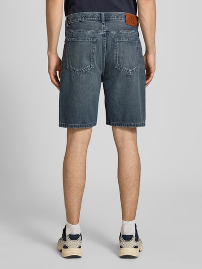 Männermodel trägt Loose Fit Jeansshorts aus reiner Baumwolle von Calvin Klein Jeans w stylizowanej na denim z naszywką z logo, szlufkami, 5 kieszeniami i zapięciem na guzik i kryty zamek błyskawiczny, materiał: bawełna; Ganzkörperansicht Rückansicht