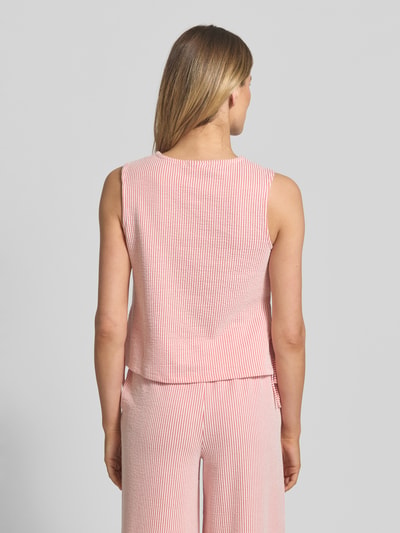 Kobiece model prezentuje Blusentop mit seitlicher Schnürung Modell 'STRIPLO' od Vila, mieszanka materiałów z udziałem bawełny, krój straight fit, okrągły dekolt, długość tyłu w rozmiarze S: 49 cm, cienkie pionowe paski w kolorach różowym i białym, tekstura lekko prążkowana, zdjęcie całej sylwetki z tyłu.