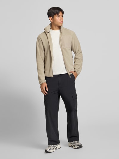 Männermodel trägt Fleecejacke mit Zweiwege-Reißverschluss Modell 'MASON' von JACK & JONES in Beige, Regular Fit, Logo, Ganzkörperansicht von vorne.