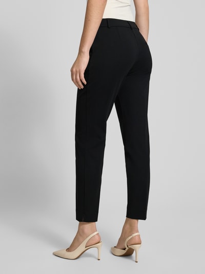 Frauenmodel trägt Stoffhose mit Gesäßtasche von Comma, Viskose-Mix mit Stretch-Anteil, lockerer Schnitt, Bundfalten, Ganzkörperansicht Rückansicht.