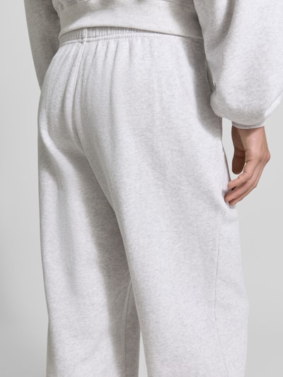 Männermodel trägt Sweatpants mit Eingrifftaschen Modell 'ATUBAY' von American Vintage aus Baumwoll-Elasthan-Mix in Hellgrau, Detailaufnahme Rückansicht. Relaxed-Fit, elastischer Bund, Tunnelzug, Herren, angenehme Textur.