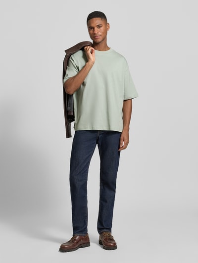 Männermodel trägt Relaxed Fit T-Shirt aus reiner Baumwolle Modell 'RELEXASPEN' von SELECTED HOMME in Hellgrün, unifarben, Feinripp, Ganzkörperansicht von vorne.