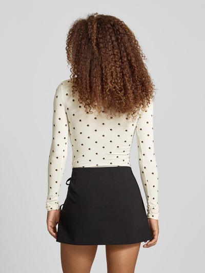 Vrouwenmodel draagt Longsleeve met Label-Stitching model 'Maeve' van OH APRIL, wit met zwarte stippen, slim fit, rugaanzicht, damesmode.
