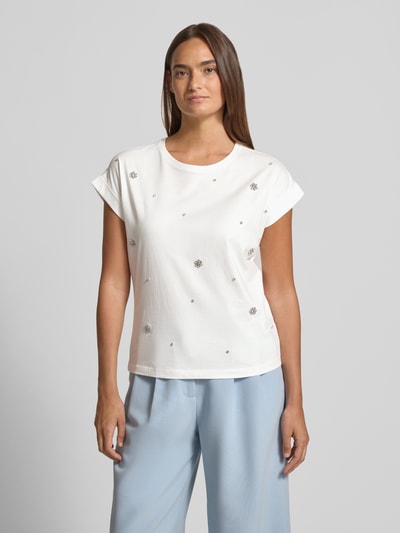 Frauenmodel trägt T-Shirt mit Ziersteinbesatz und Rundhalsausschnitt von Christian Berg Woman aus Reine Baumwolle im Regular-Fit, in Weiß mit Rückenlänge 50 cm bei Größe S, Ganzkörperansicht von vorne.