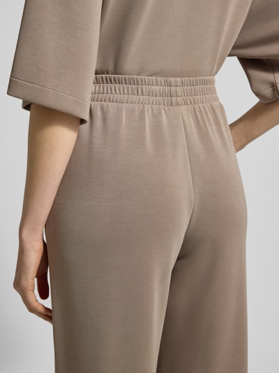Kobiece modelka ma na sobie Spodnie z Mieszanka modalu z elastycznym pasem od Jake*s Casual, wpuszczane kieszenie, krój relaxed fit, długość wewnętrzna nogawki 79 cm, szerokość w rozmiarze S 35 cm, zbliżenie na tył.