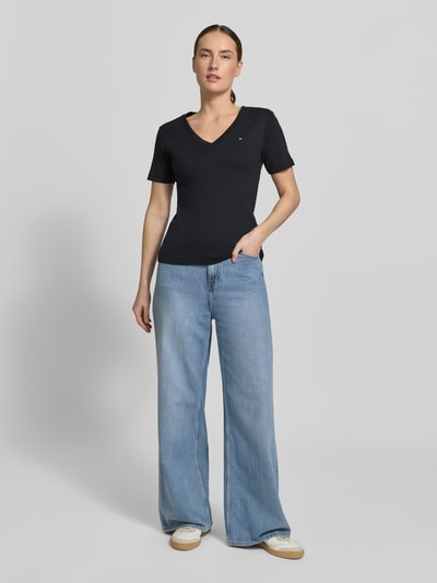Frauenmodel trägt Slim Fit T-Shirt aus reiner Baumwolle von Tommy Hilfiger, Optik: Unifarben, Logo-Stitching, V-Ausschnitt, Kurzarm, Materialverarbeitung: Jersey, Ganzkörperansicht von vorne.
