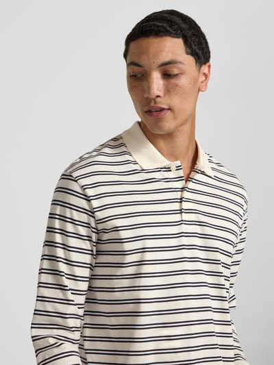 Männermodel trägt Regular fit poloshirt met streepmotief model 'CASSIS' van Jack & Jones van puur katoen, shirt met lange mouwen, knoopsluiting, ruglengte bij maat M 66 cm, kleuren crème en donkerblauw, eenvoudige textuur, nahaufnahme bovenlichaam.