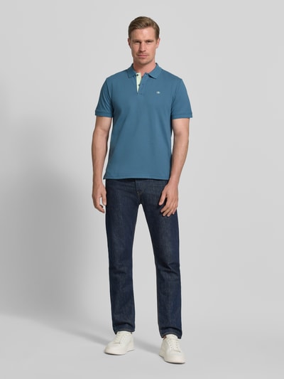 Męski model nosi Regular Fit Poloshirt aus reiner Baumwolle od Tom Tailor, efekt: jednolity kolor, krój regular fit, wyhaftowane logo, kołnierzyk polo, zapięcie na 2 guziki, krótki rękaw, wykończenie z rozcięciami po bokach, wykończenie materiału: pika, materiał: czysta bawełna, widok całej sylwetki z przodu.