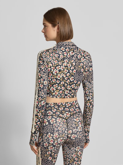 Frauenmodel trägt Slim Fit Sport-Top mit floralem Muster von adidas Sportswear, dunkle Grundfarbe, bunte Blumen, Ganzkörperansicht Rückansicht.