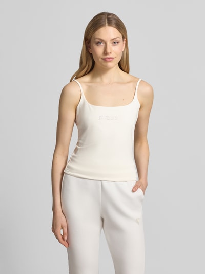 Frauenmodel trägt Trägertop mit Logo Modell 'ORTENSIA' von Guess Activewear aus Baumwoll-Elasthan-Mix, Regular-Fit, Karree-Ausschnitt, cremefarbener Stoff mit glatter Textur, Rückenlänge bei Größe S: 29 cm, Ganzkörperansicht von vorne.