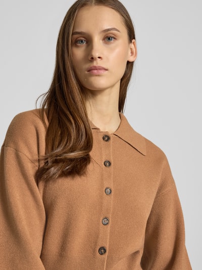 Frauenmodel trägt Strickjacke aus Viskose-Mix Modell 'SHYLA' von Noisy May, lockere Passform, Umlegekragen, durchgehende Knopfleiste, 3/4-Arm, gerippte Abschlüsse, Nahaufnahme Oberkörper.