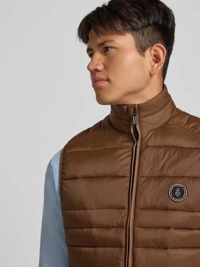 Mannenmodel draagt bodywarmer met opstaande kraag en ritszakken Model 'KINGSLEY' van JACK & JONES, Nahaufnahme Oberkörper, regular fit, bruine kleur, context: Heren bodywarmer van JACK & JONES, regular fit, opstaande kraag, model 'KINGSLEY', ritssluiting, ritszakken, ruglengte maat M: 65 cm, schouderbreedte maat M: 42 cm, borstwijdte maat M: 43 cm.