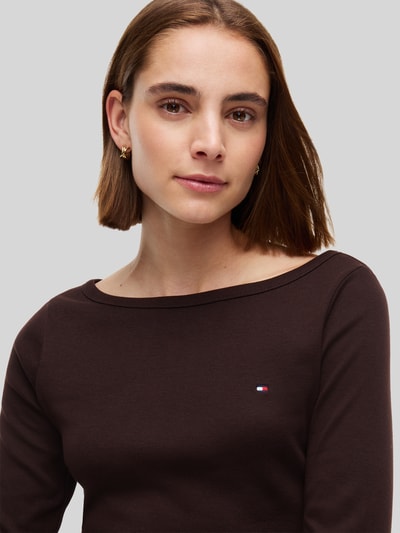 Frauenmodel trägt Slim Fit Langarmshirt aus reiner Baumwolle von Tommy Hilfiger in Dunkelbraun, glatte Struktur, Nahaufnahme Oberkörper, Damen T-Shirt von Tommy Hilfiger.