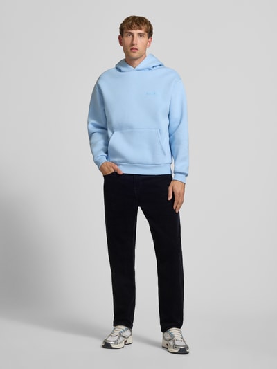 Männermodel trägt Straight Fit Hose aus reiner Baumwolle in Cord-Optik von Carhartt Work In Progress, dunkler Stoff, Ganzkörperansicht von vorne.
