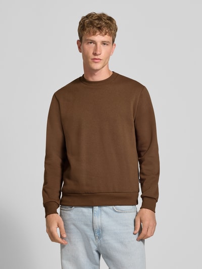 Männermodel trägt Regular Fit Sweatshirt mit Baumwoll-Anteil Modell 'Bradley' von JACK & JONES in Braun, Material-Mix, Ganzkörperansicht von vorne.