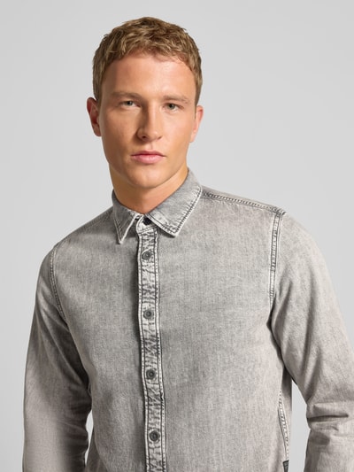 Męski model nosi Freizeithemd mit Knopfleiste od G-Star Raw, szara bawełna, slim fit, kołnierz kent, zapięcie na guziki, zbliżenie górnej części ciała.