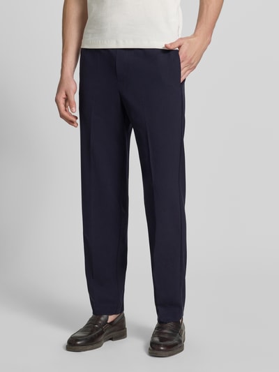 Męski model nosi Relaxed Fit Sweatpants mit Viskose-Anteil od Lindbergh, granatowy kolor, elastyczna mieszanka materiałów z dodatkiem wiskozy, spodnie dresowe z kantami, szerokość w rozmiarze M 41 cm, długość wewnętrzna nogawki 79 cm, widok z przodu, ujęcie całej sylwetki.